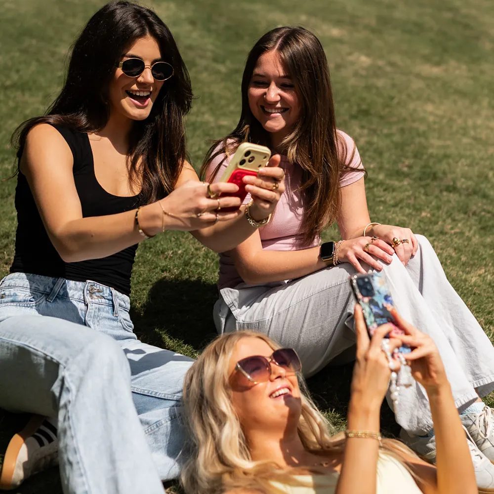 Friends playing on phones on grass outside