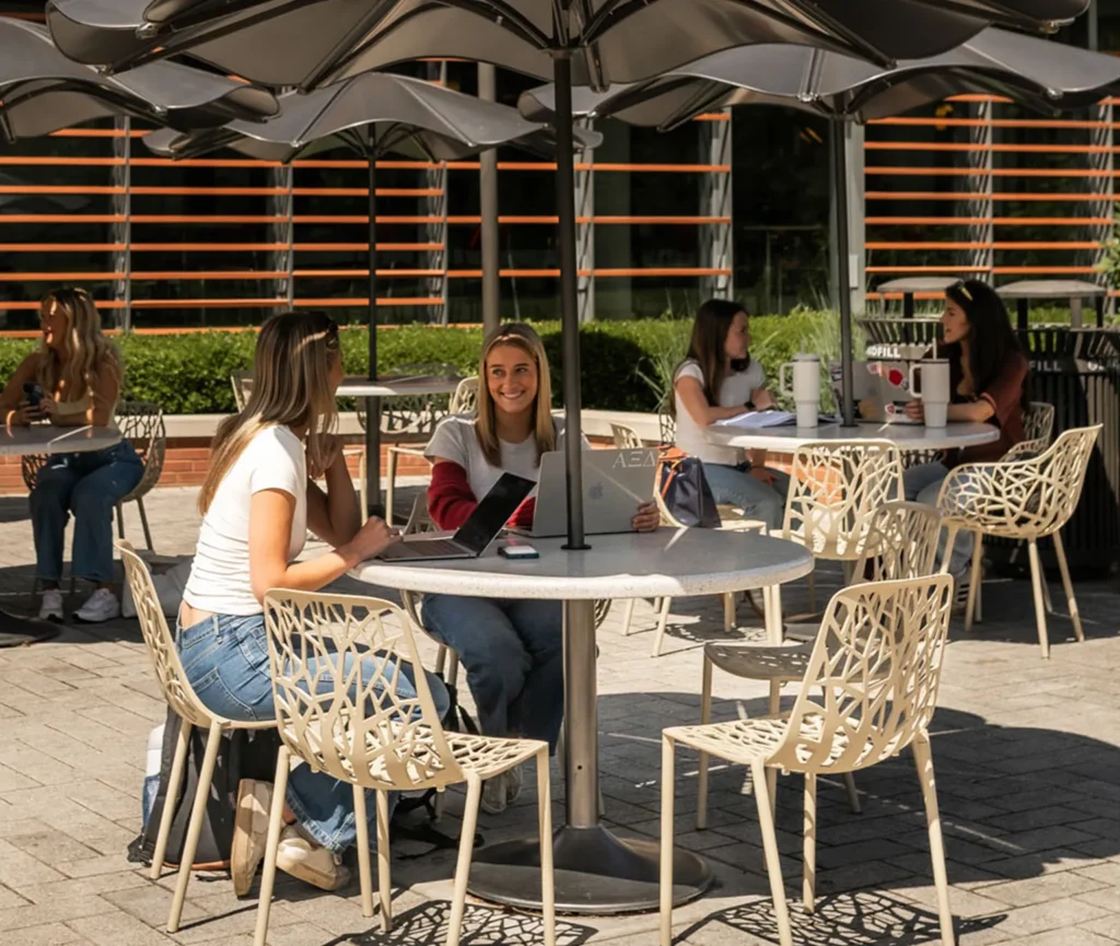 Students sitting chatting on tables outside on NC State campus