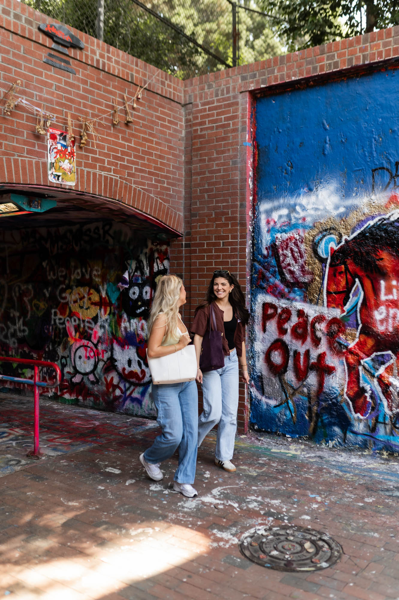 Friends walking in front of underpass with graffiti and street art