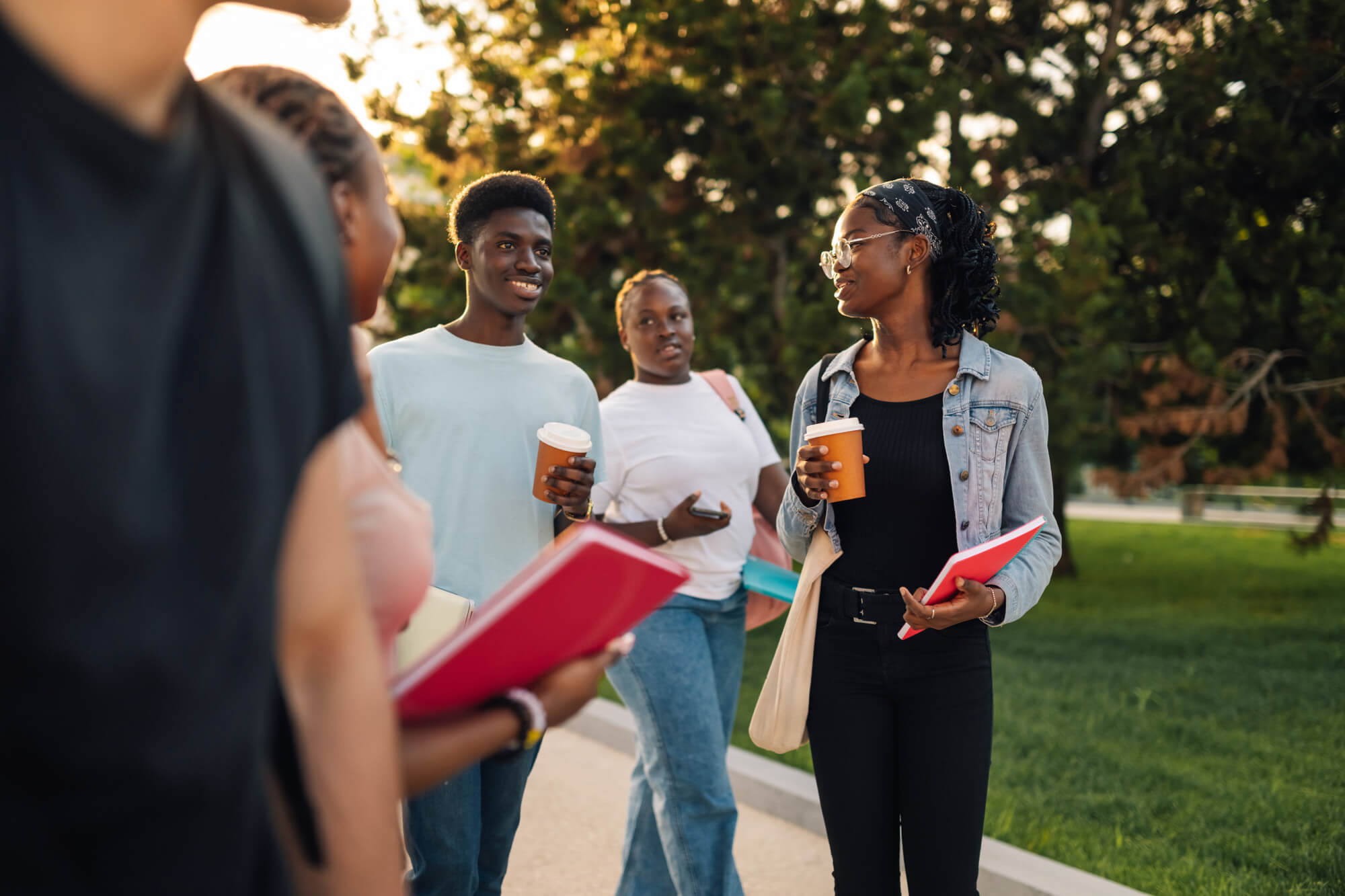 Group of friends walking outside holding coffee and notebooks