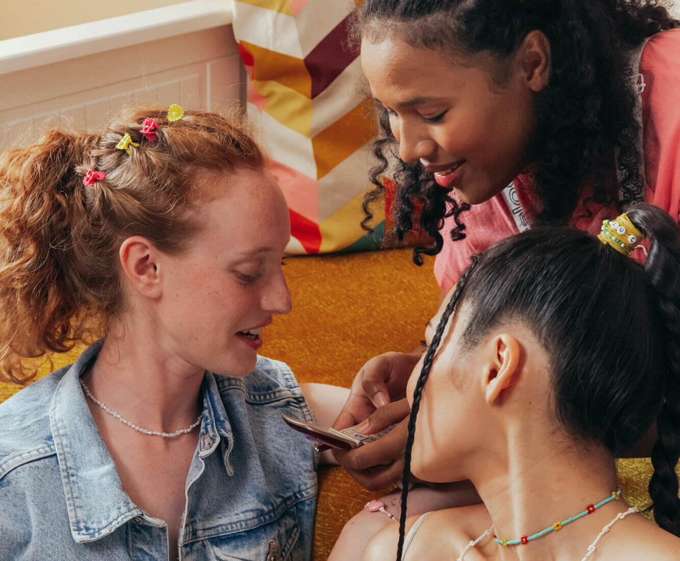 Three female friends gathered looking at phone