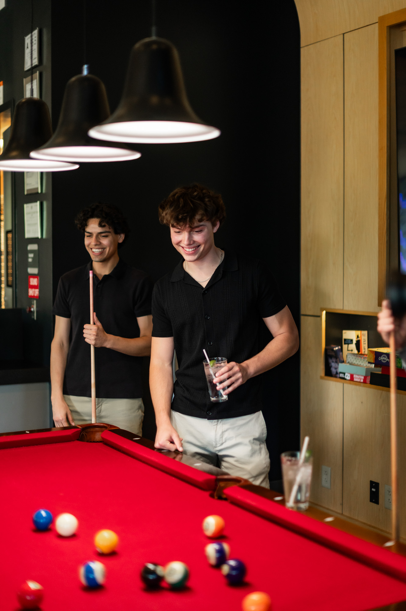 Two friends playing billiards with drinks at bar