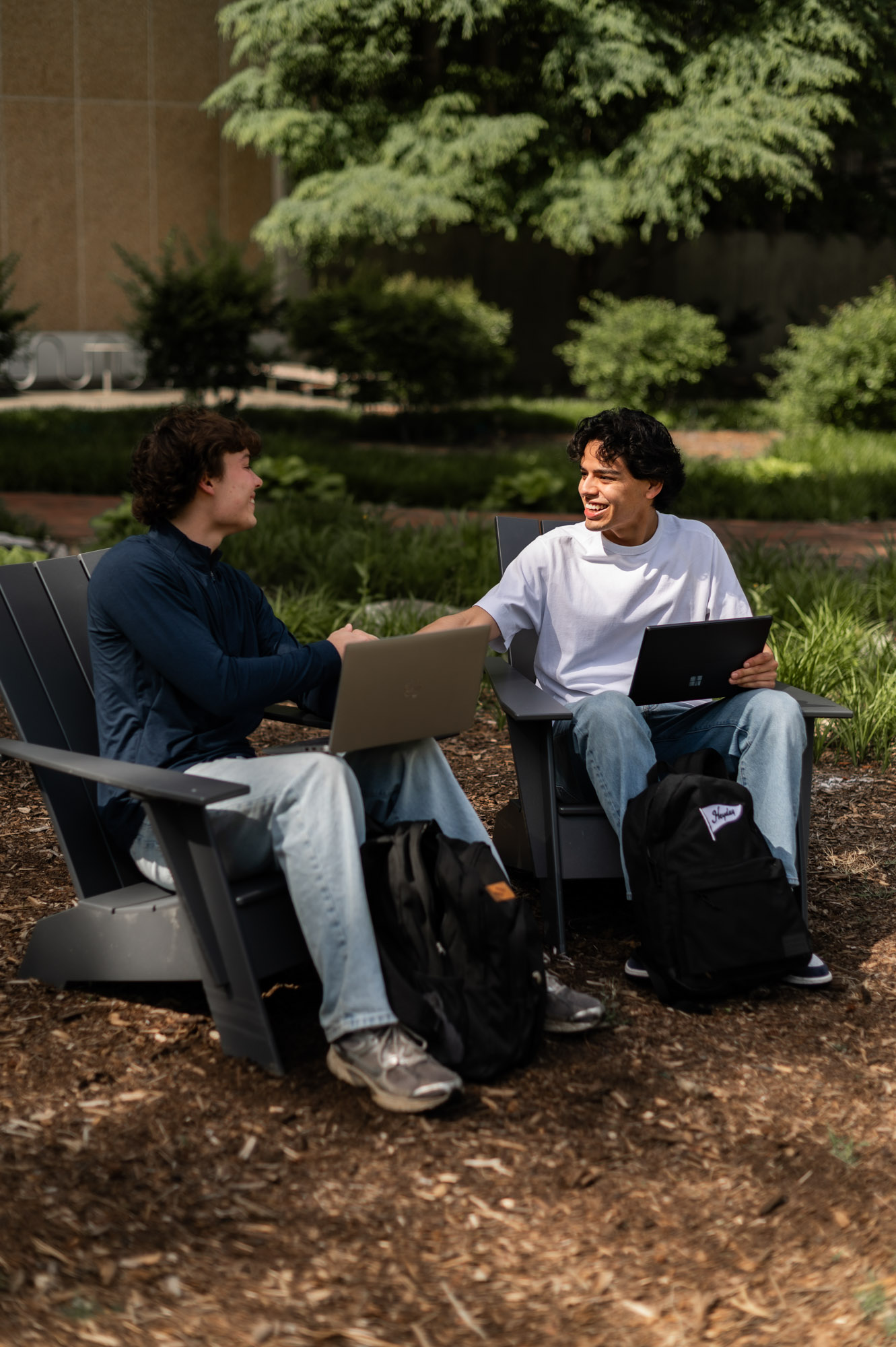 Two friends sitting in adirondack chairs outside studying
