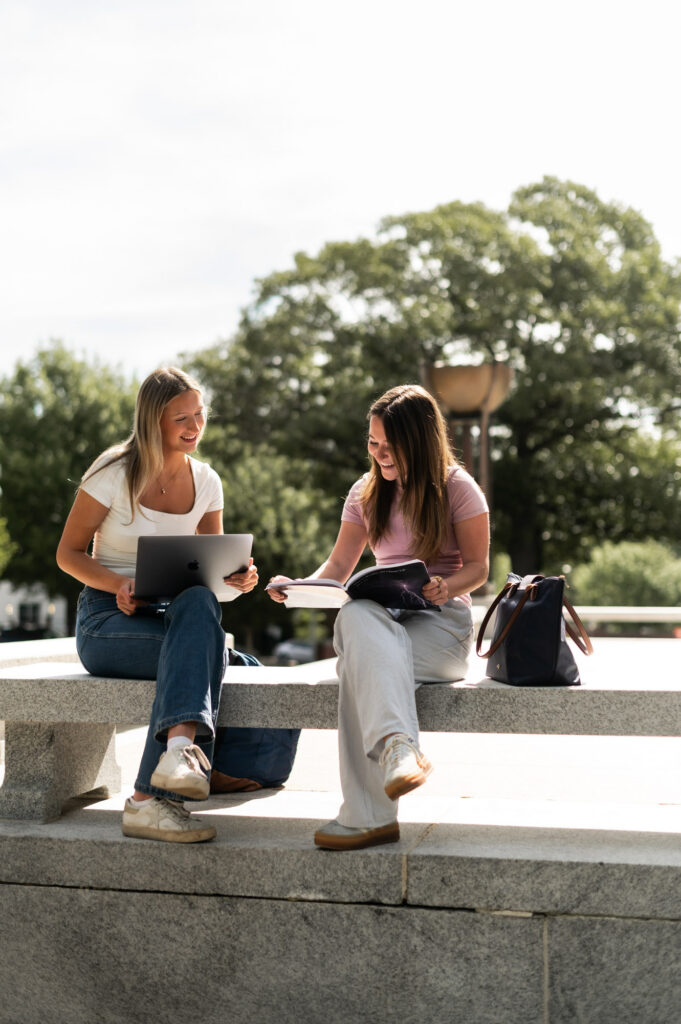 Two friends studying sitting on bench outside